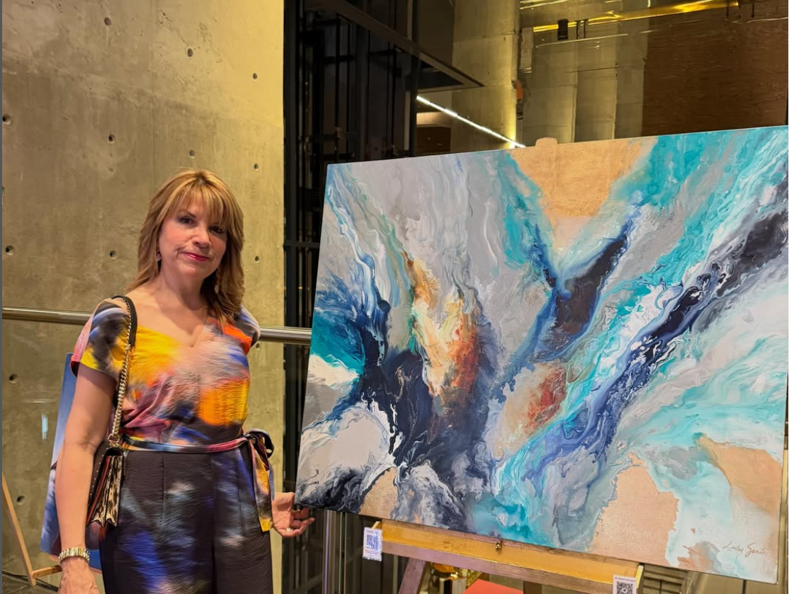 Luly Santos junto a su obra abstracta en azules y turquesas
